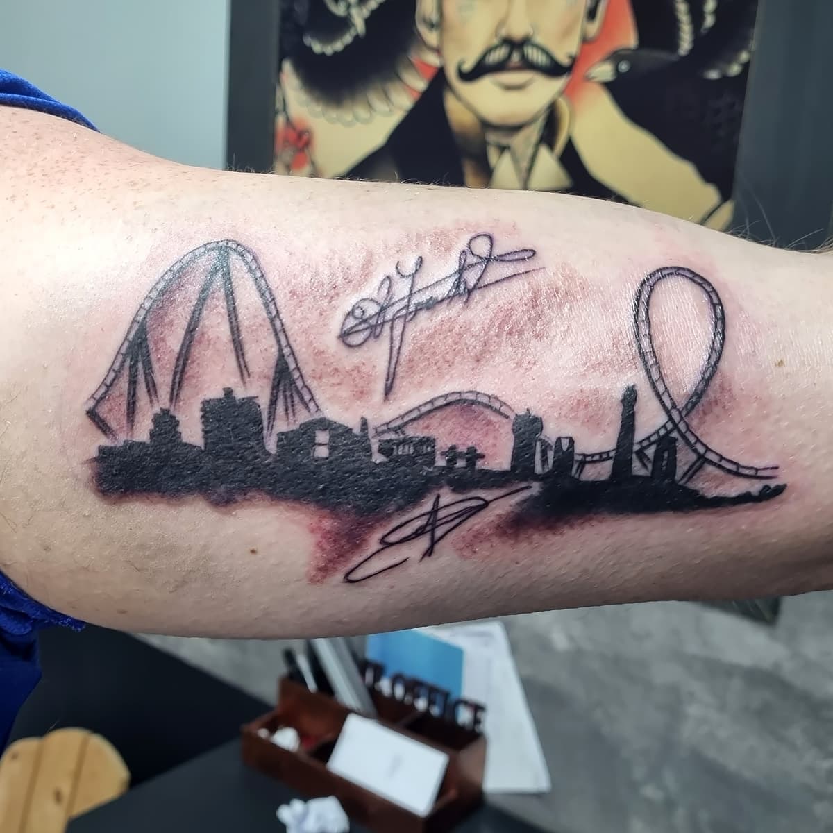 Skyline met achtbanen en handtekeningen op bovenarm.