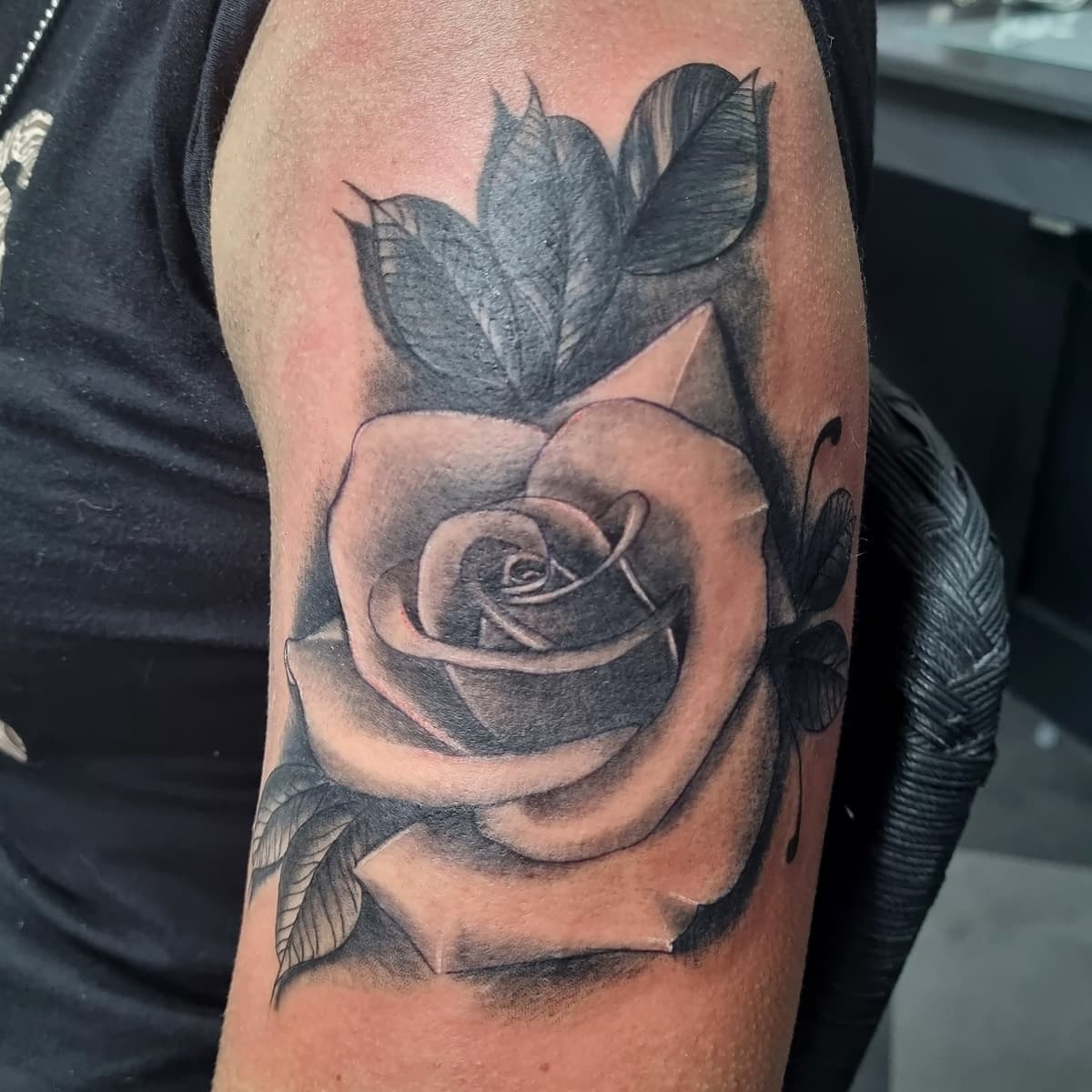Zwart-wit realistische roos met bladeren op bovenarm.