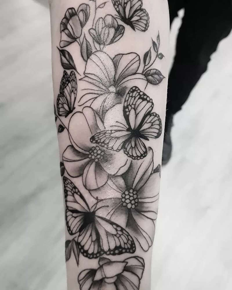 Zwart-wit tattoo van vlinders en bloemen op de onderarm.