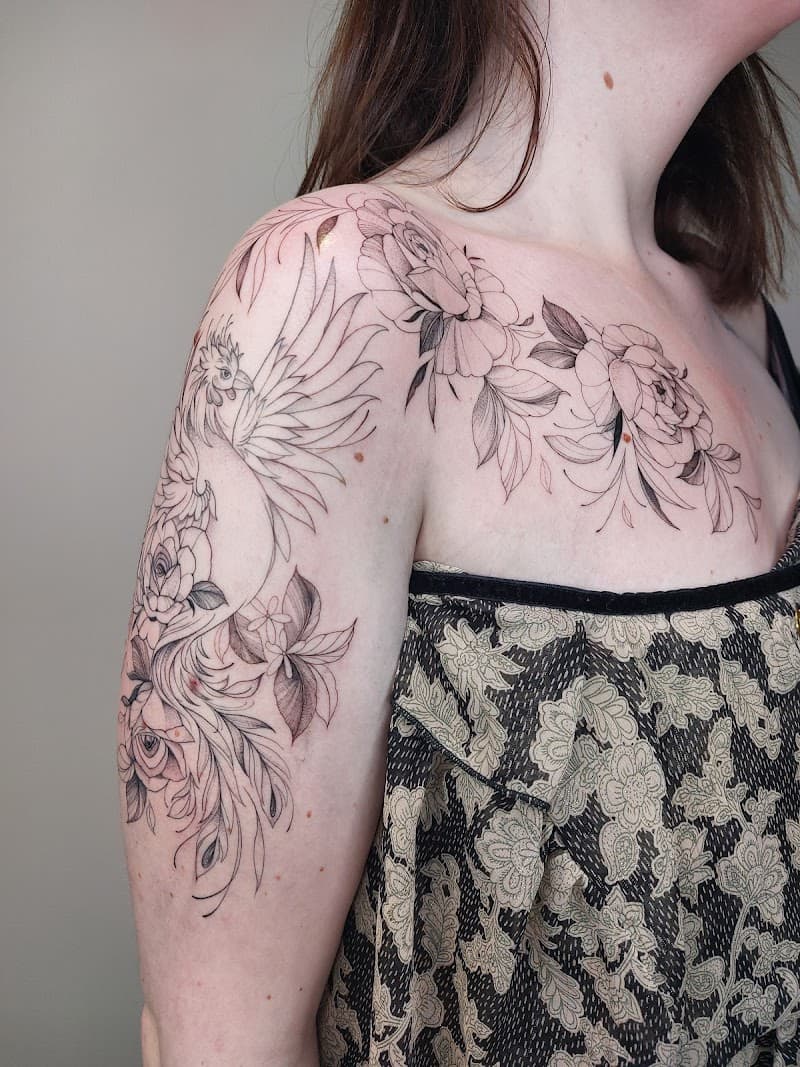 Fineline tattoo van een feniks en bloemen op schouder en borst.