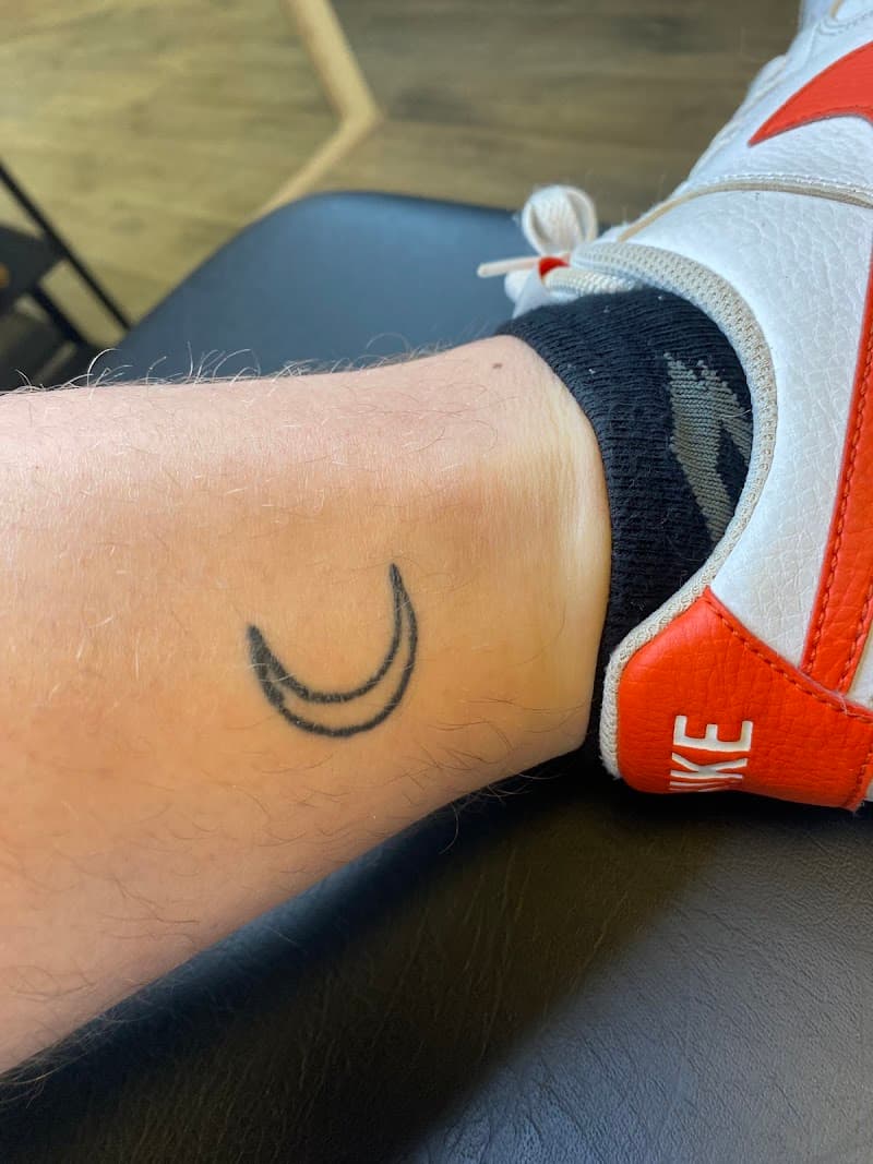 Minimalistische halve maan tattoo op de enkel.