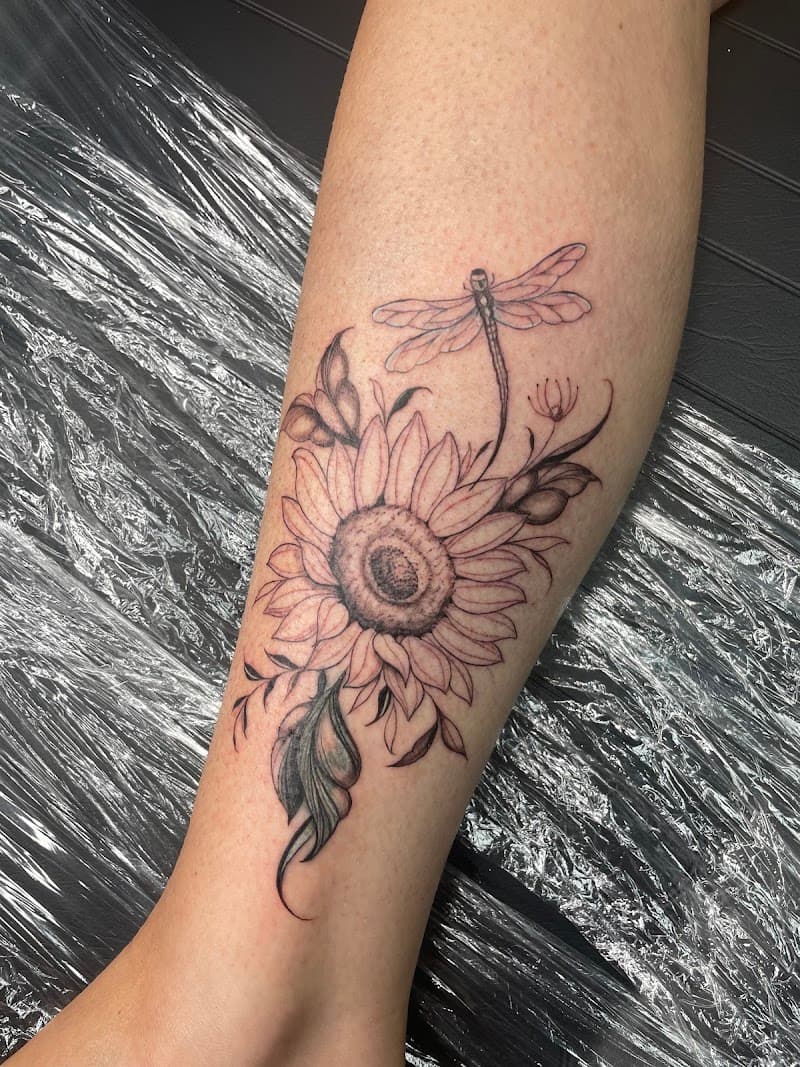 Fineline zonnebloem en libel tattoo op onderbeen.