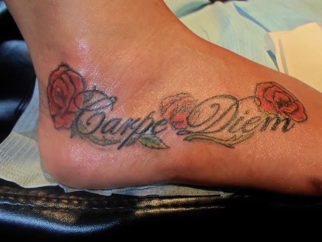 "Carpe Diem" tekst met rode rozen op de voet.