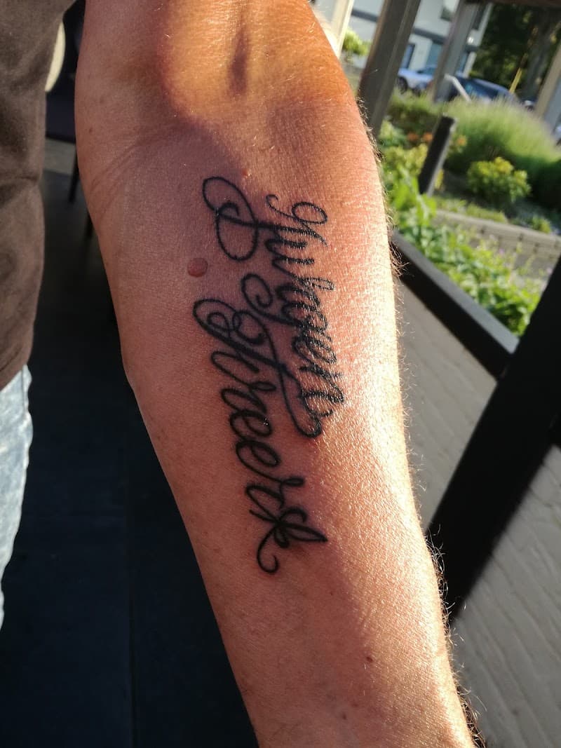 Zwarte 'Jürgen Streeck' naam tattoo in sierlijke letters op onderarm.