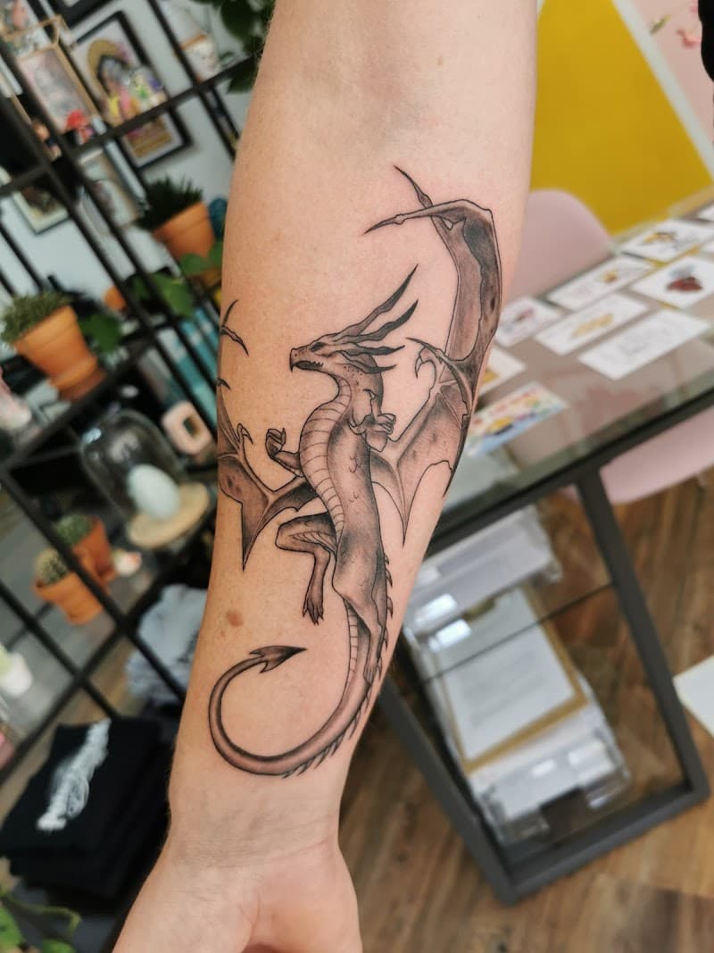 Gedetailleerde zwart-wit draak tattoo op de onderarm.