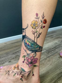 Kleurrijke kievit met bloemen op enkel en voet.