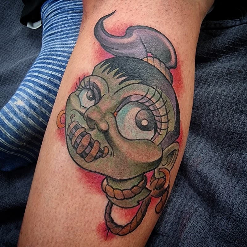 Neo-traditionele tattoo van een groen cartoon hoofd met touw.