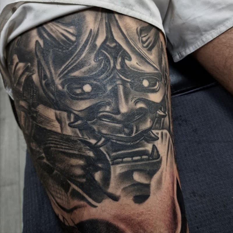 Grote zwart-wit Hannya masker tattoo op bovenbeen.