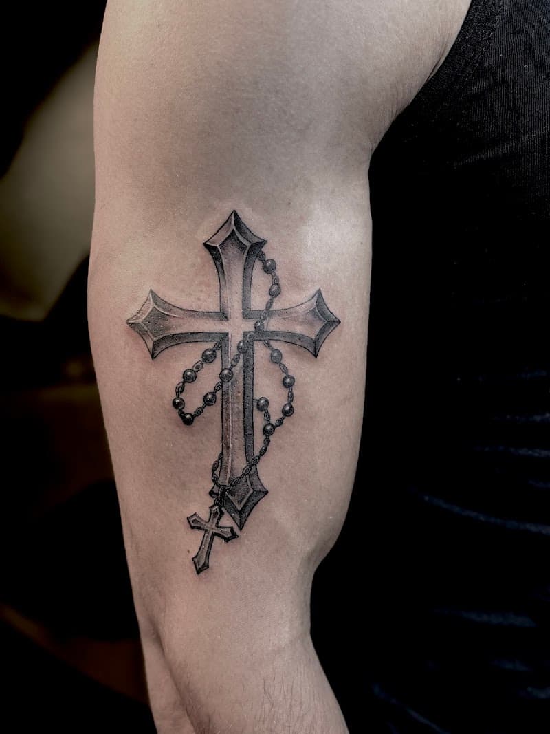 Zwart-wit kruis met rozenkrans op bovenarm.