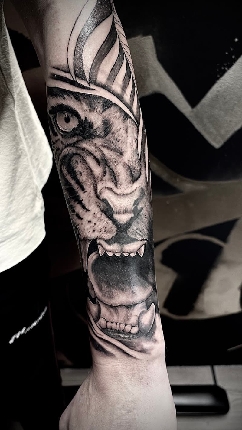 Realistische zwart-wit tijgerkop tattoo op onderarm.