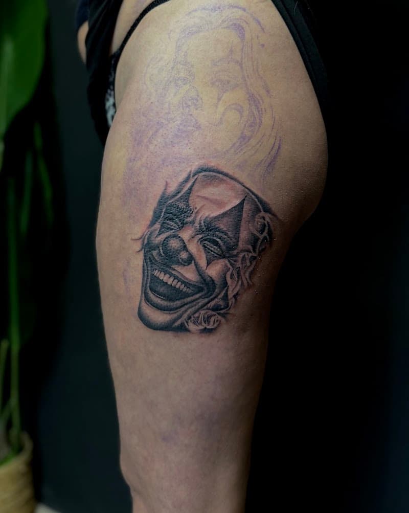 Realistische lachende clown masker tattoo op bovenbeen.