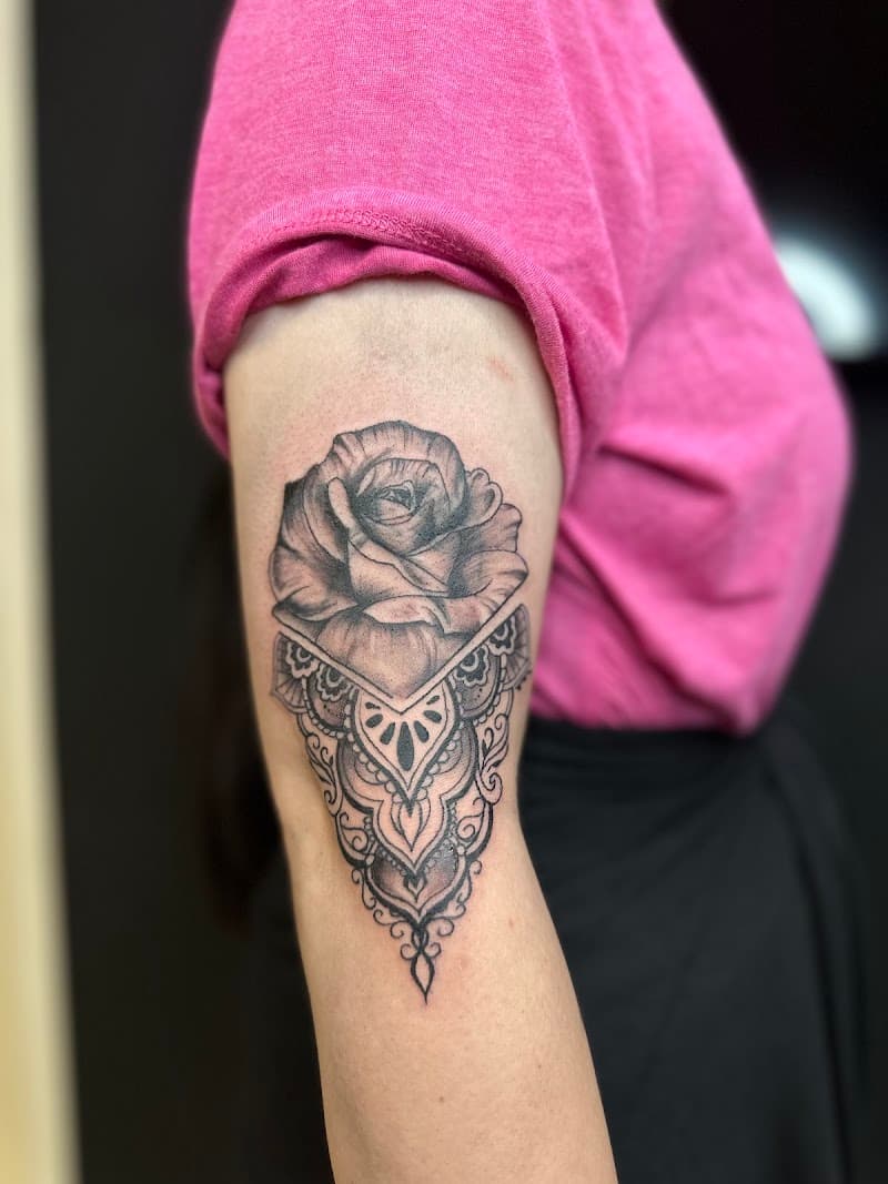 Zwart-wit roos met geometrisch mandala patroon op bovenarm.
