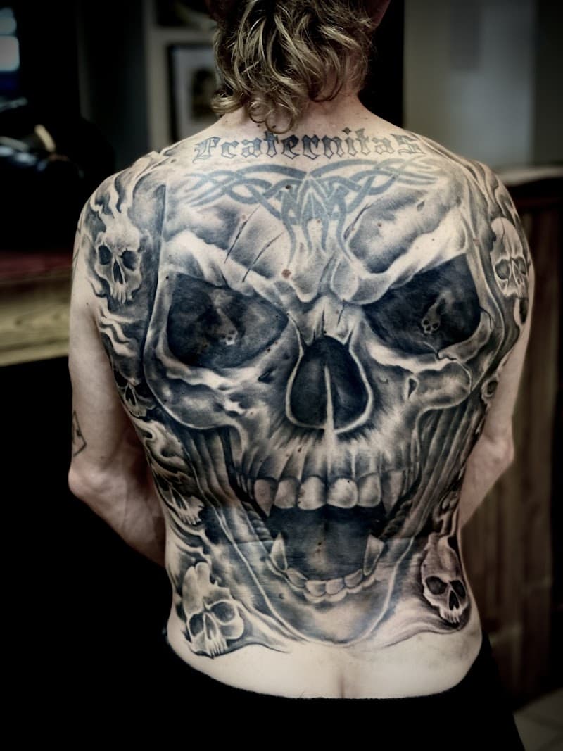 Grote zwart-wit schedel full-back tattoo met 'Fraternitas' tekst.