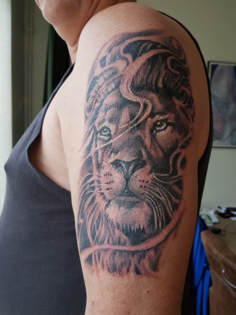 Zwart-wit realistische leeuwenkop tattoo op de bovenarm.