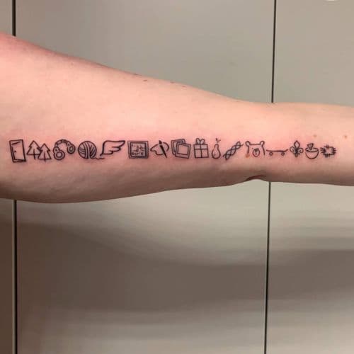 Lange rij van kleine, minimalistische symbolen op de onderarm.