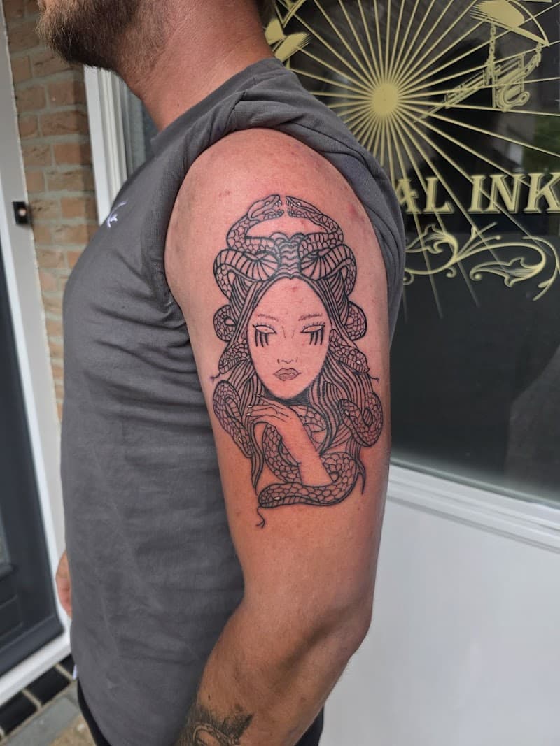 Illustratieve Medusa tattoo met slangenhaar op de bovenarm.