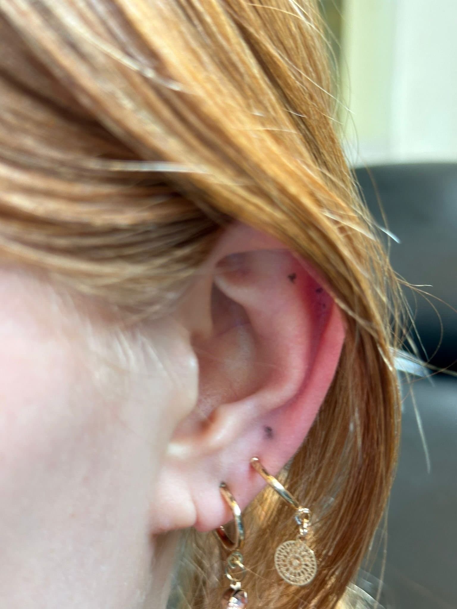 Twee kleine minimalistische stippen op het oor.