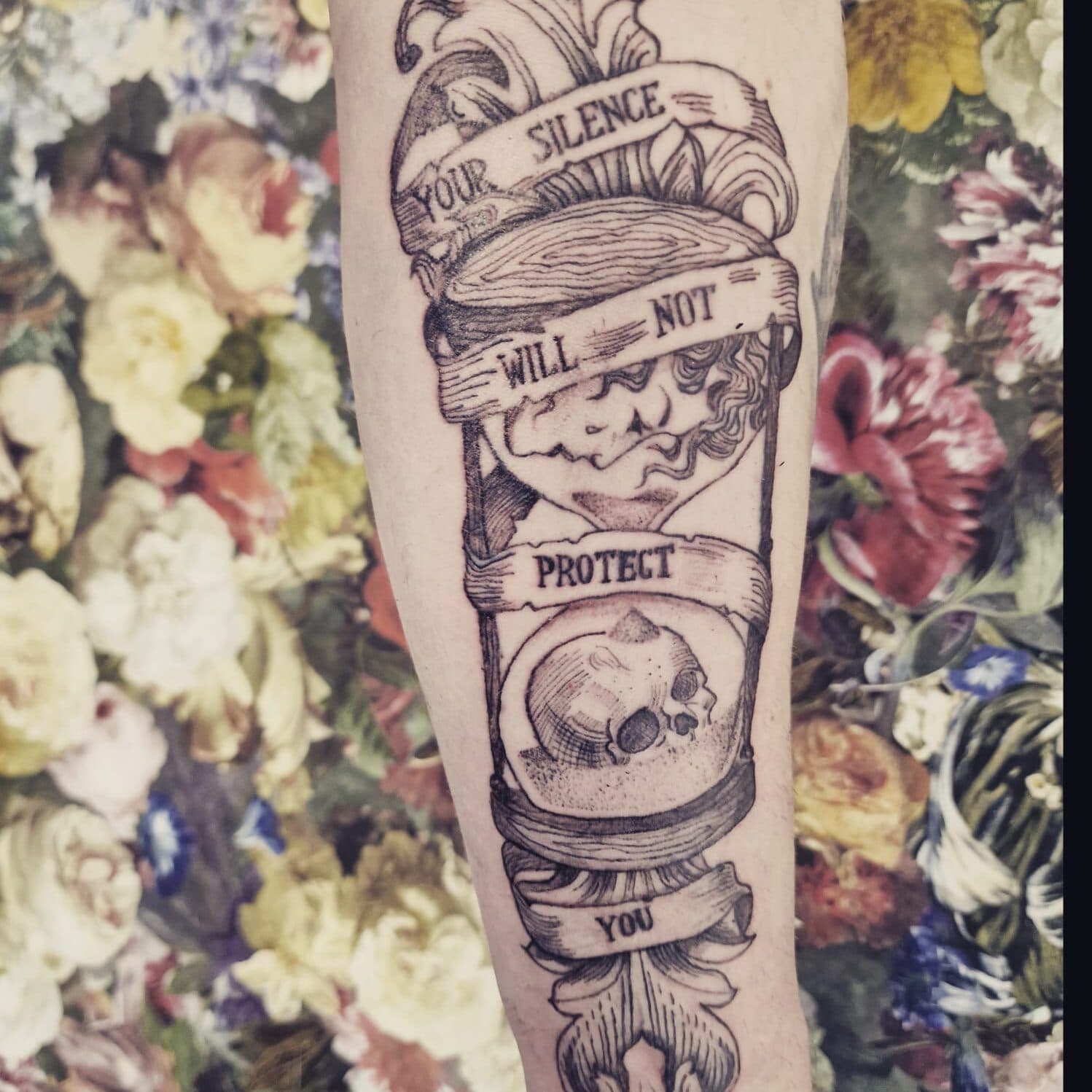 Zwart-wit zandloper tattoo met schedel en tekst 'YOUR SILENCE WILL NOT PROTECT YOU'.