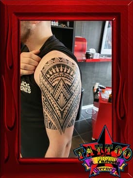 Grote tribal tattoo met geometrische patronen op de bovenarm.