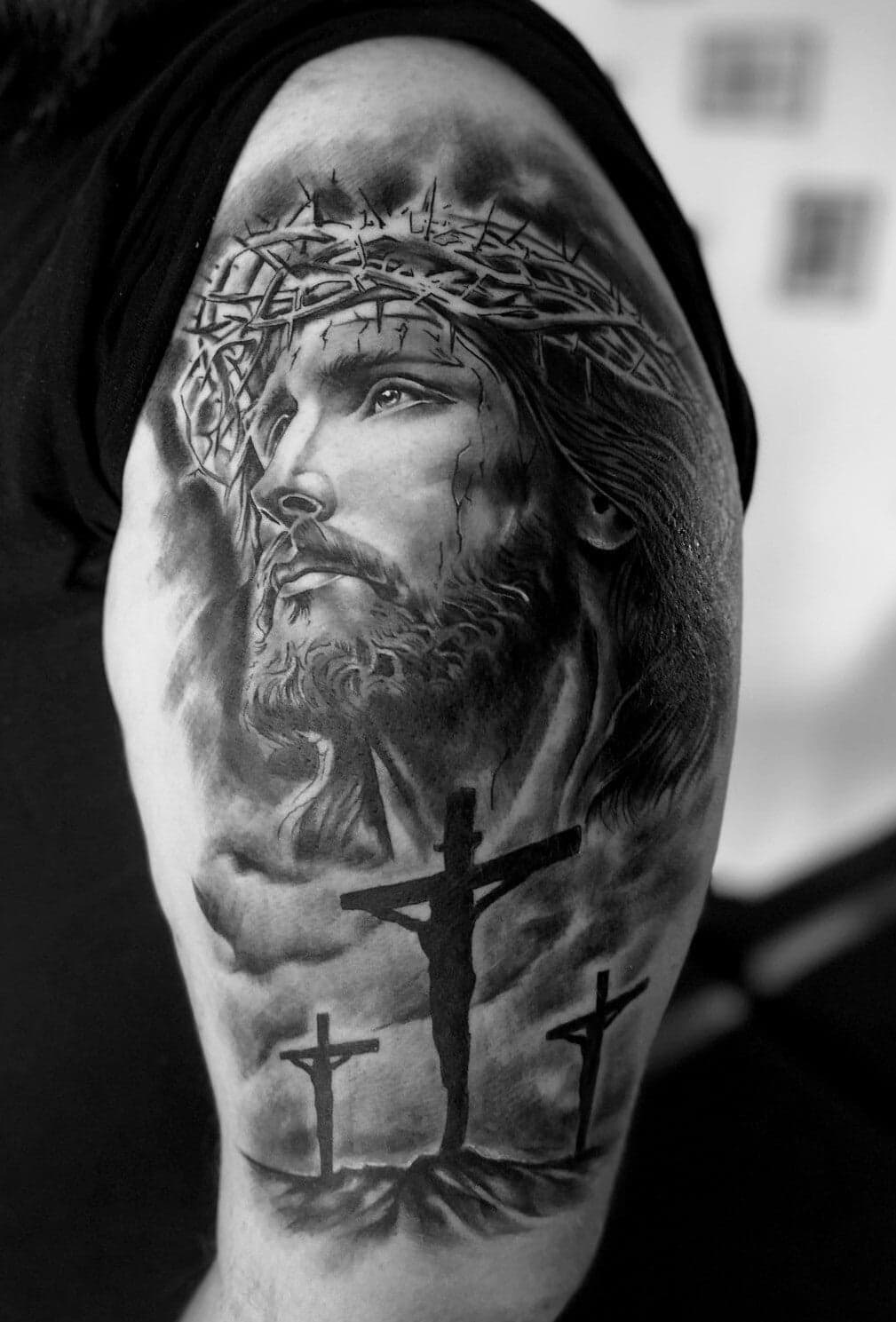 Realistisch portret van Jezus met doornenkroon en drie kruisen op de bovenarm.