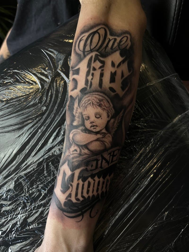 Zwart-wit tattoo van een cherubijntje met de tekst "One Life One Chance".