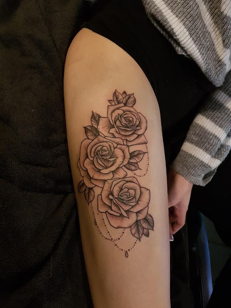 Fineline tattoo van drie rozen met bladeren en stippellijn op bovenbeen.