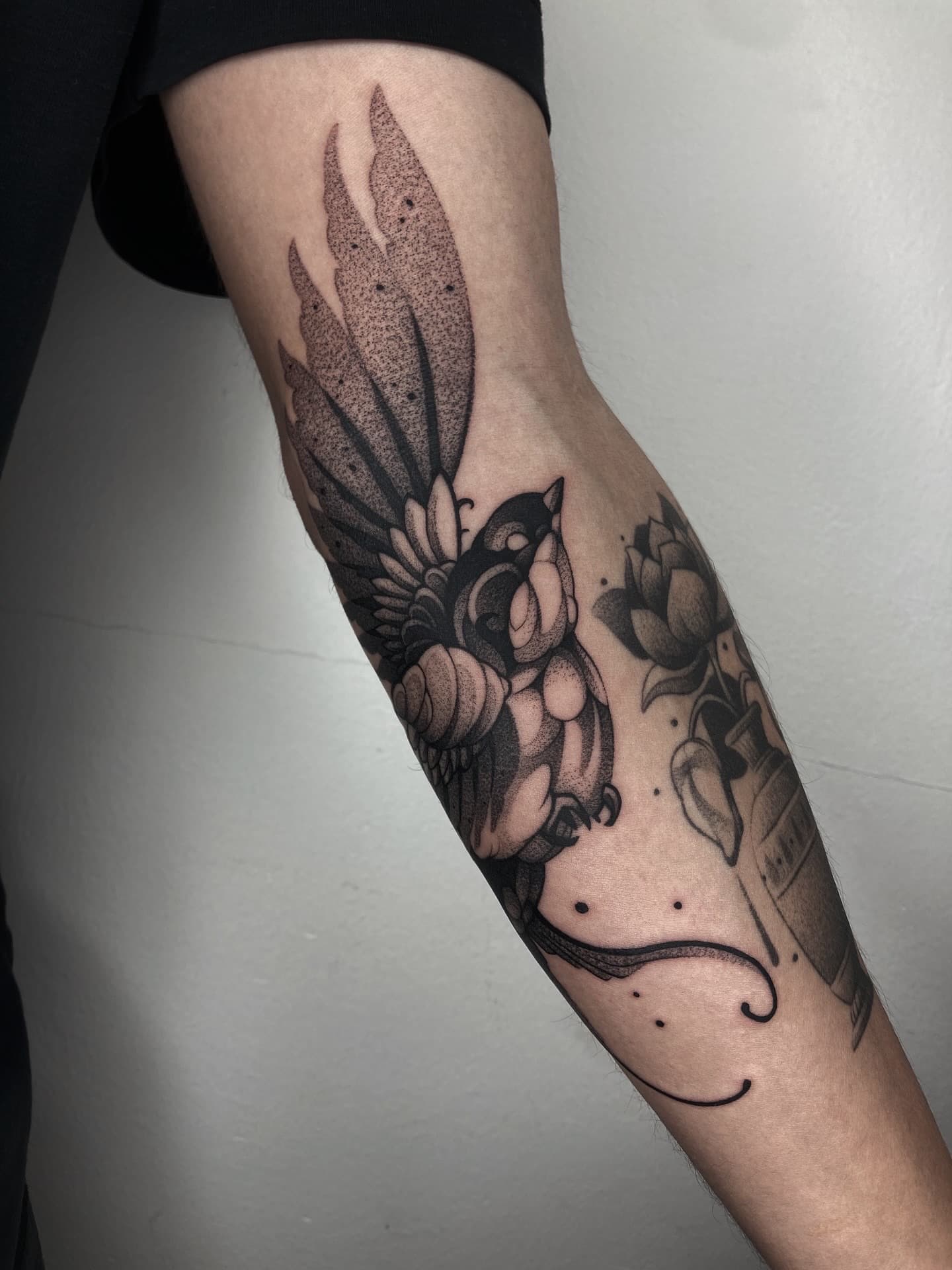 Zwart-wit dotwork tattoo van een vogel op de onderarm.