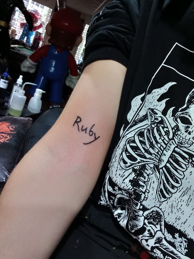 Eenvoudige 'Ruby' naam tattoo in handschrift op onderarm.