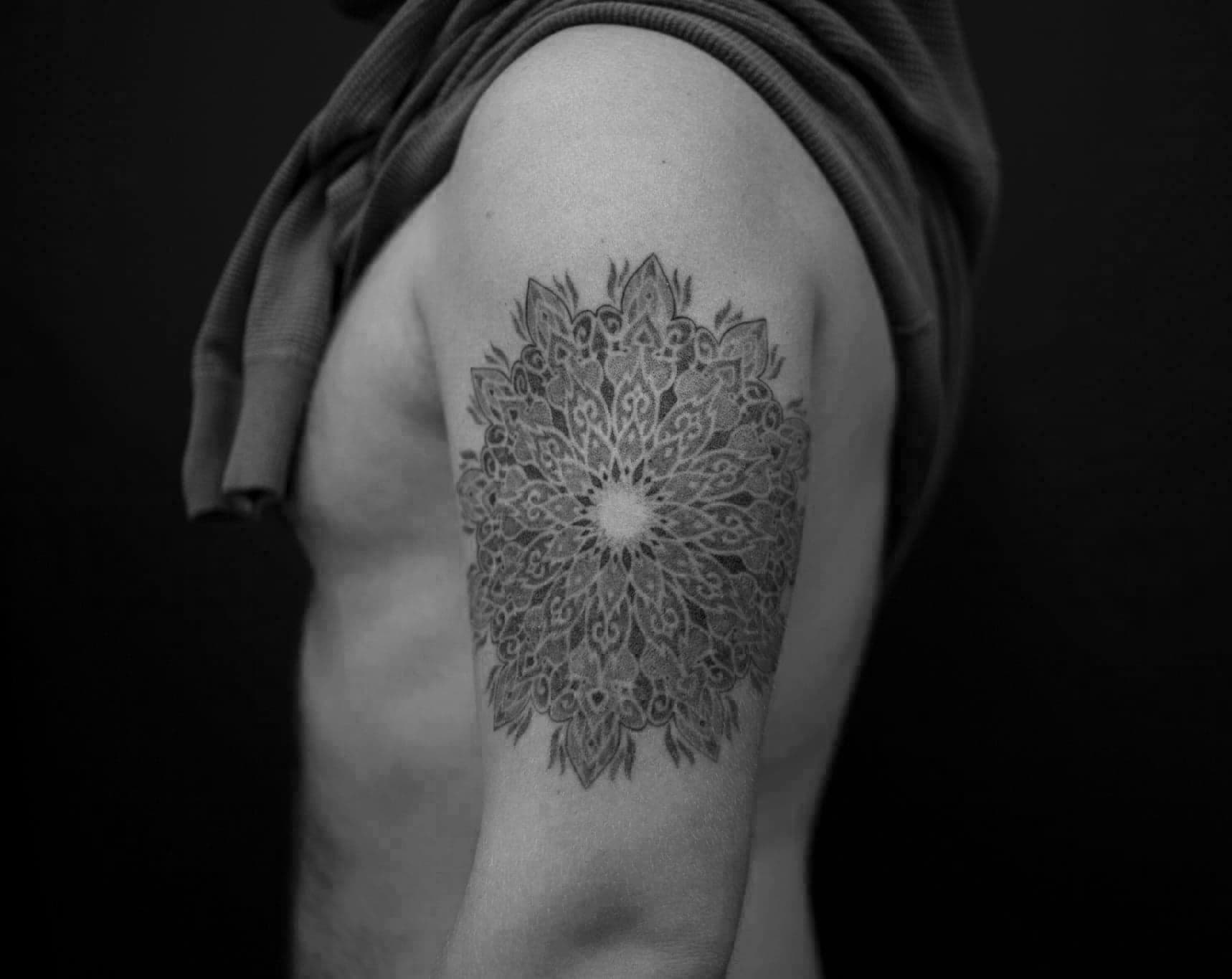 Gedetailleerde dotwork mandala tattoo op de bovenarm.