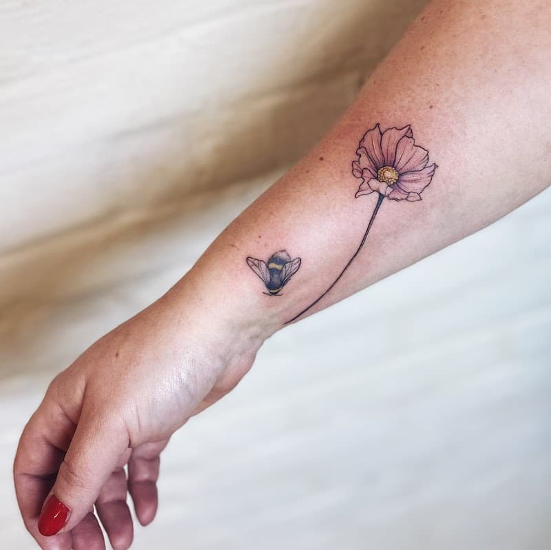Fineline tattoo van een kosmosbloem en een hommel op de onderarm.