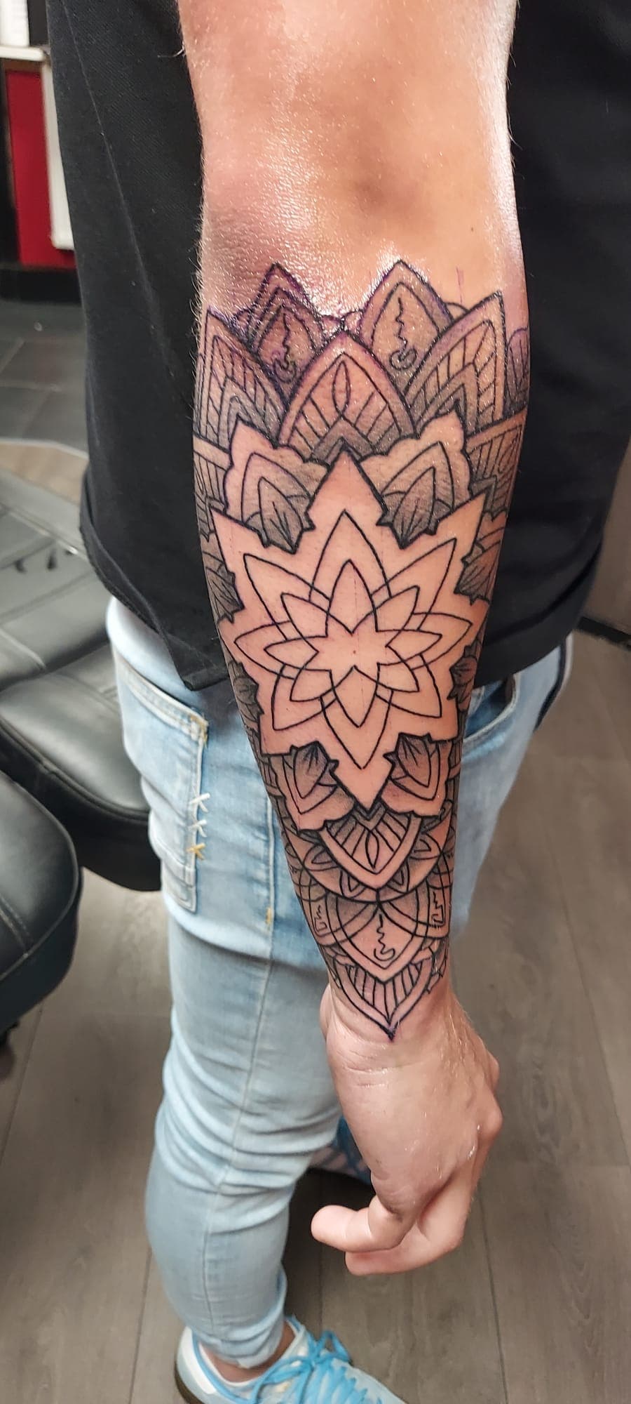 Grote mandala tattoo met geometrische patronen op onderarm.