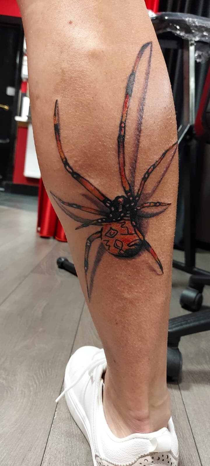 Realistische spin met D20 dobbelsteen op onderbeen.