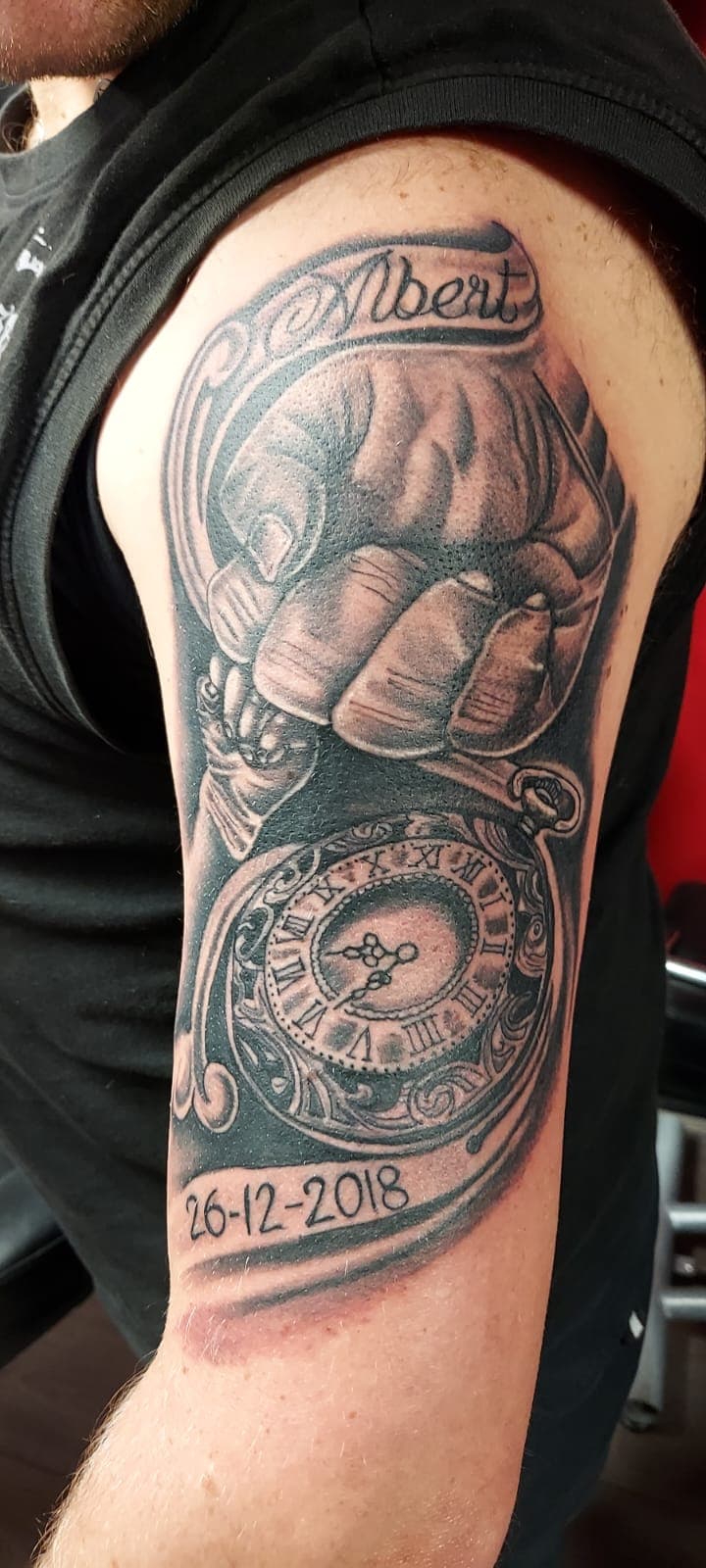 Blackwork tattoo van een vuist met een zakhorloge, naam 'Albert' en datum.