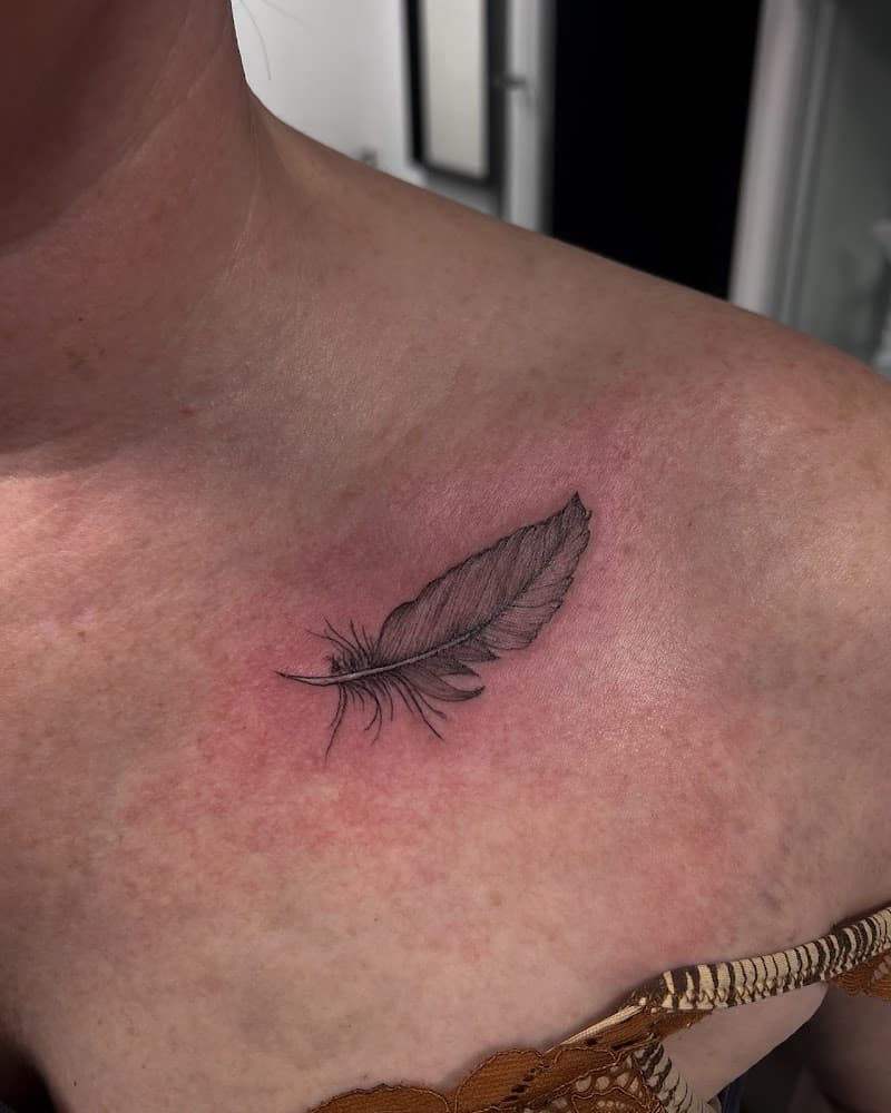 Fijne, gedetailleerde veer tattoo op het sleutelbeen.