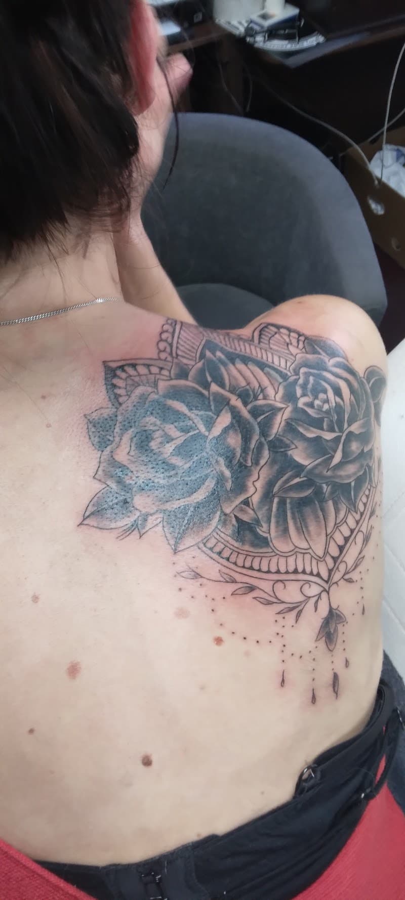 Grote blackwork tattoo van rozen en mandala op schouder en rug.