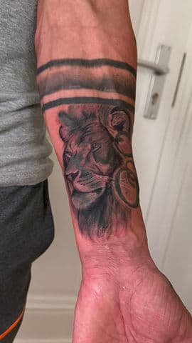 Realistische leeuwenkop met twee zwarte banden op de onderarm.
