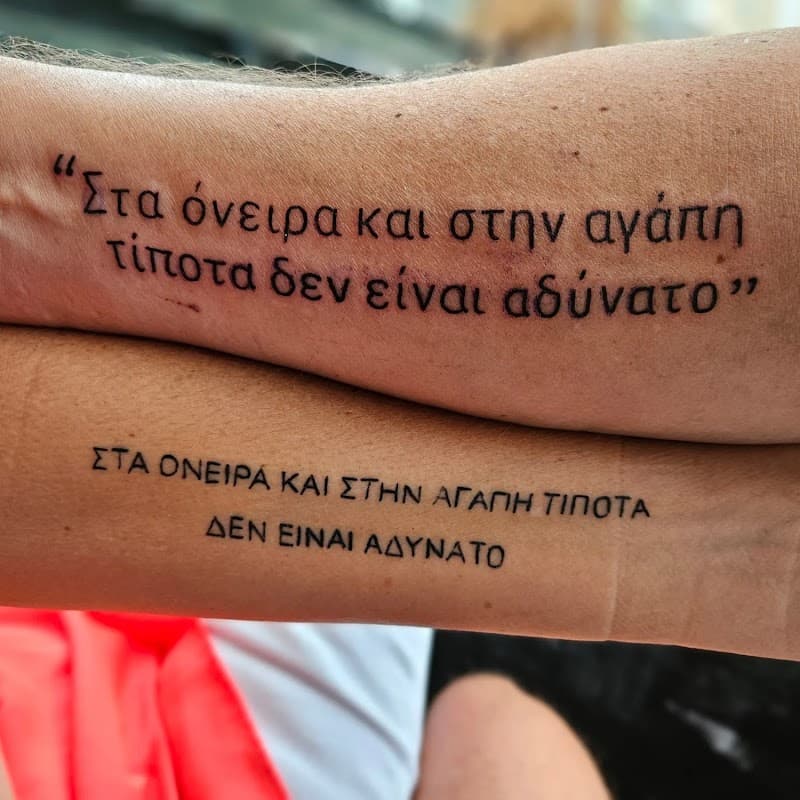 Twee Griekse tekst tattoos op onderarmen, zelfde quote.
