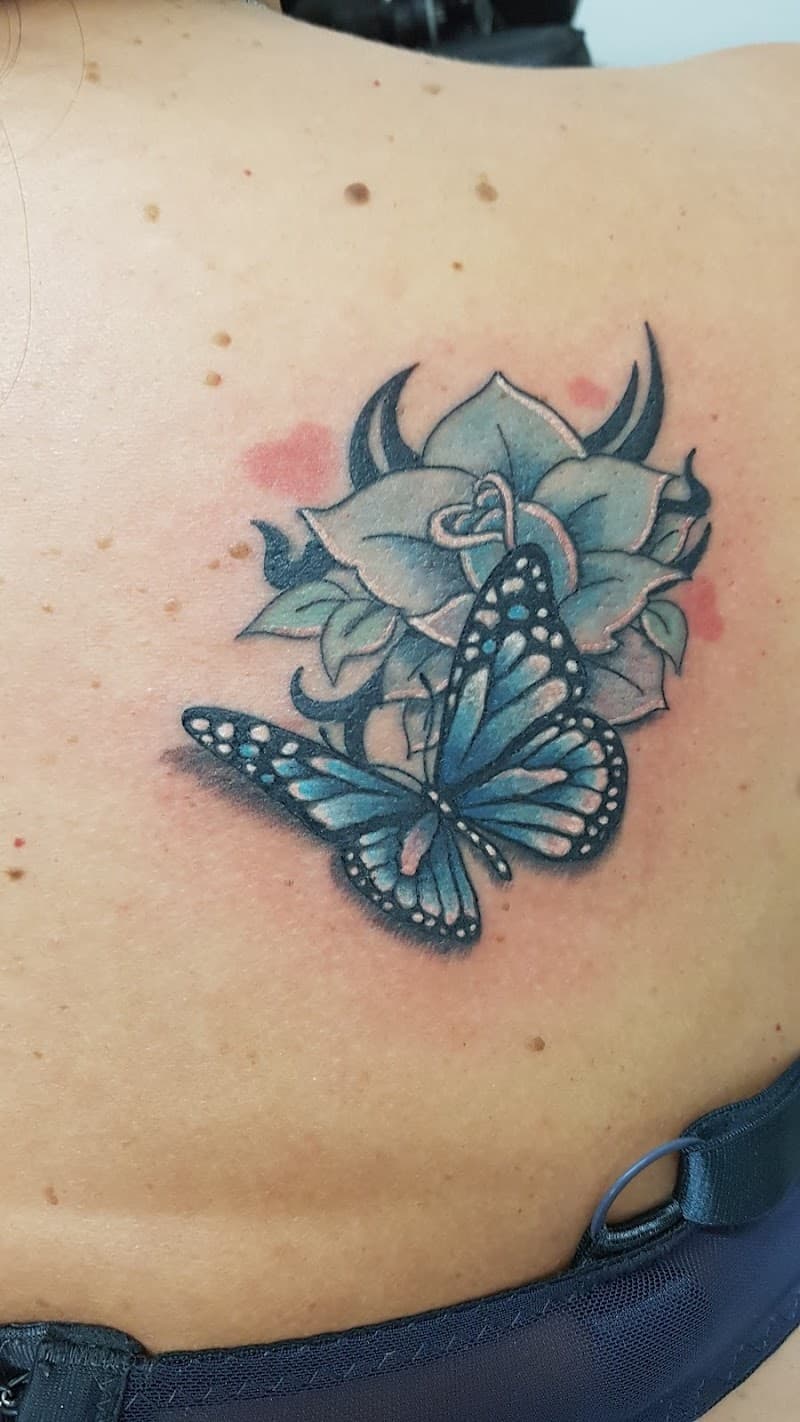 Blauwe vlinder en roos tattoo op de rug.