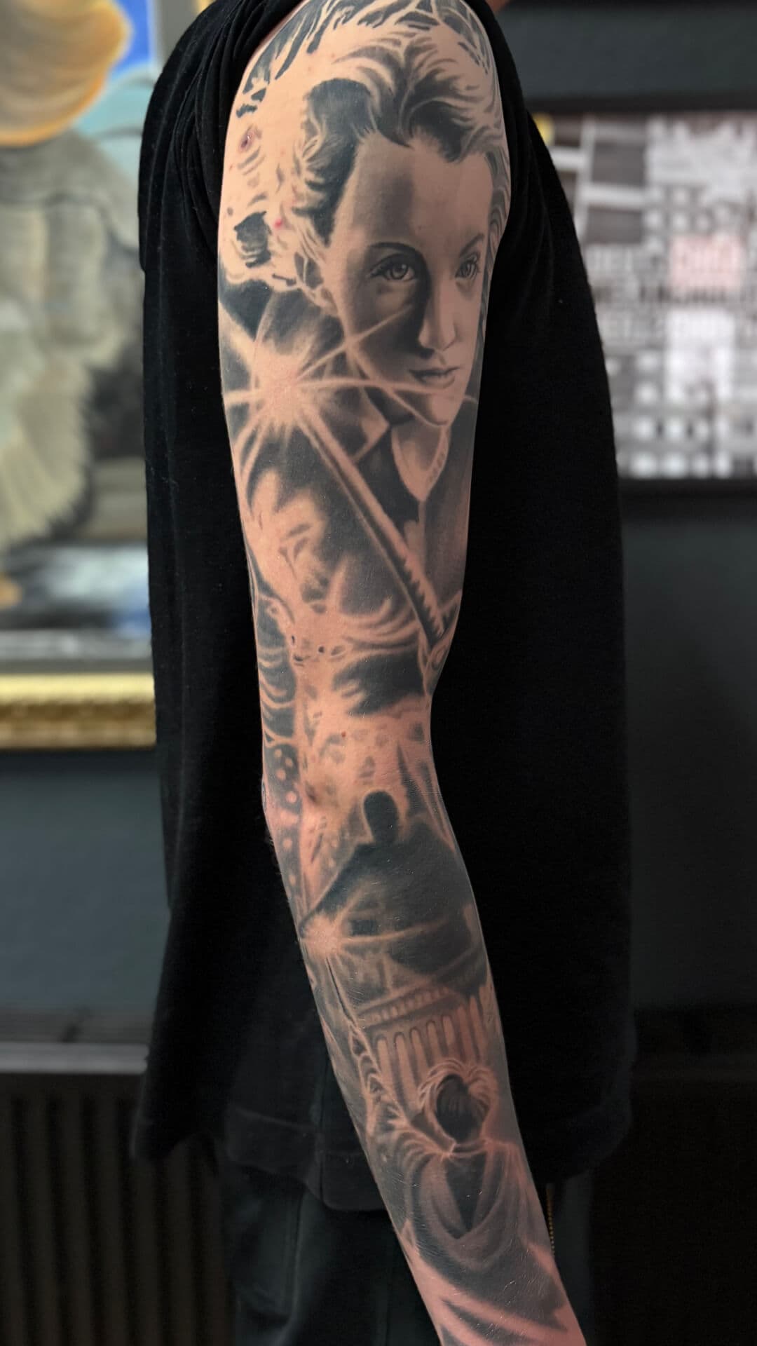 Realistische sleeve tattoo met portret en architectuur op arm.