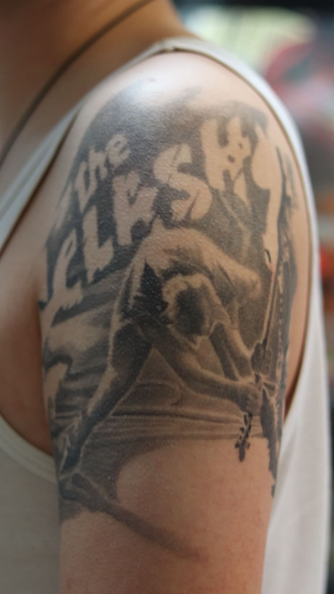 Zwart-wit tattoo van The Clash 'London Calling' album cover op bovenarm.
