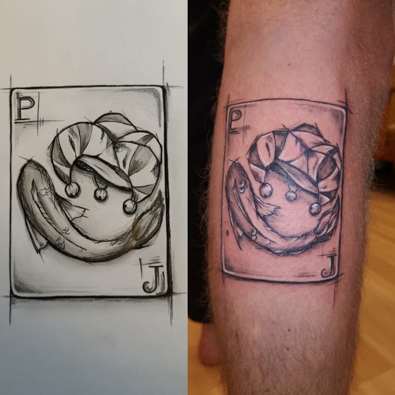 Schetsmatige speelkaart tattoo van een vis met een narrenmuts op het onderbeen.