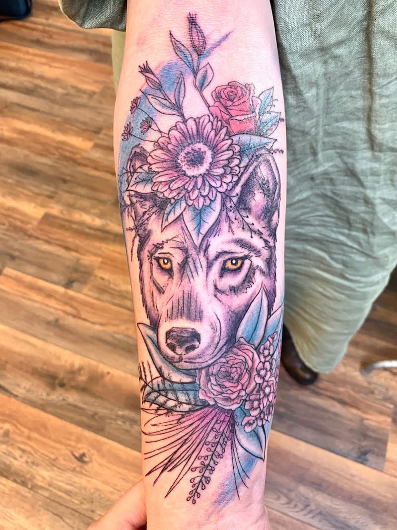 Wolf met bloemen en watercolor effect op onderarm.