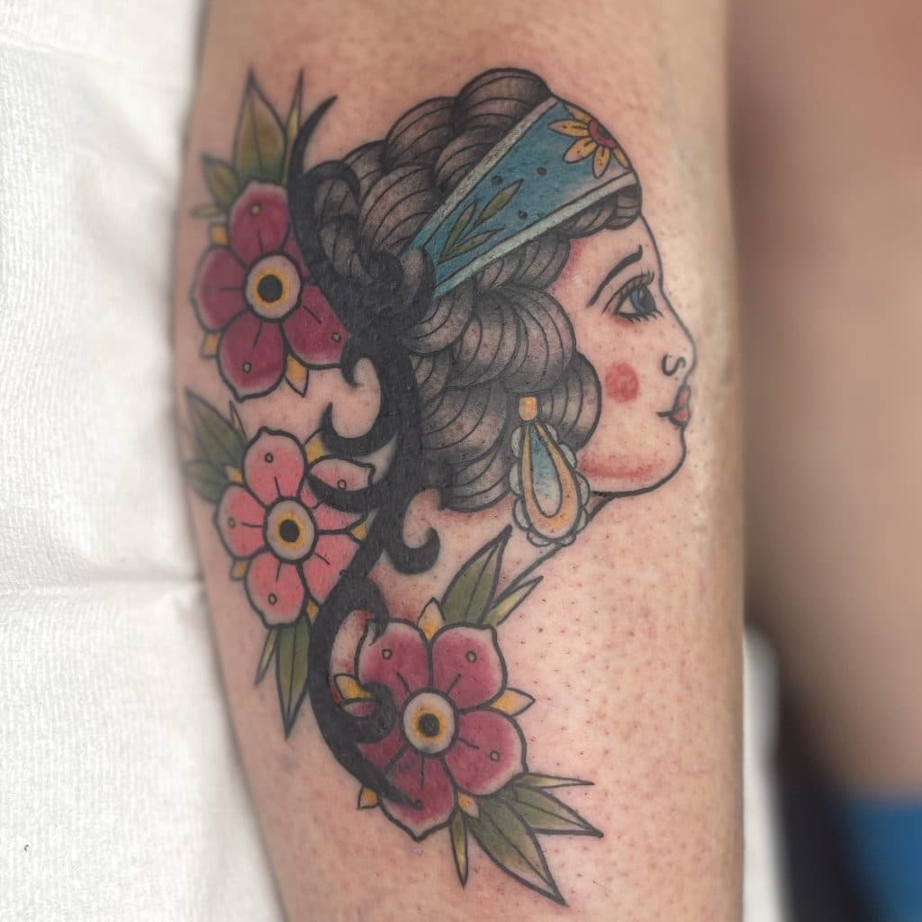Traditional tattoo van een vrouwenhoofd met bloemen.