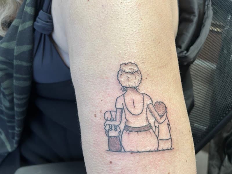 Fineline tattoo van moeder met twee kinderen op de rug gezien.