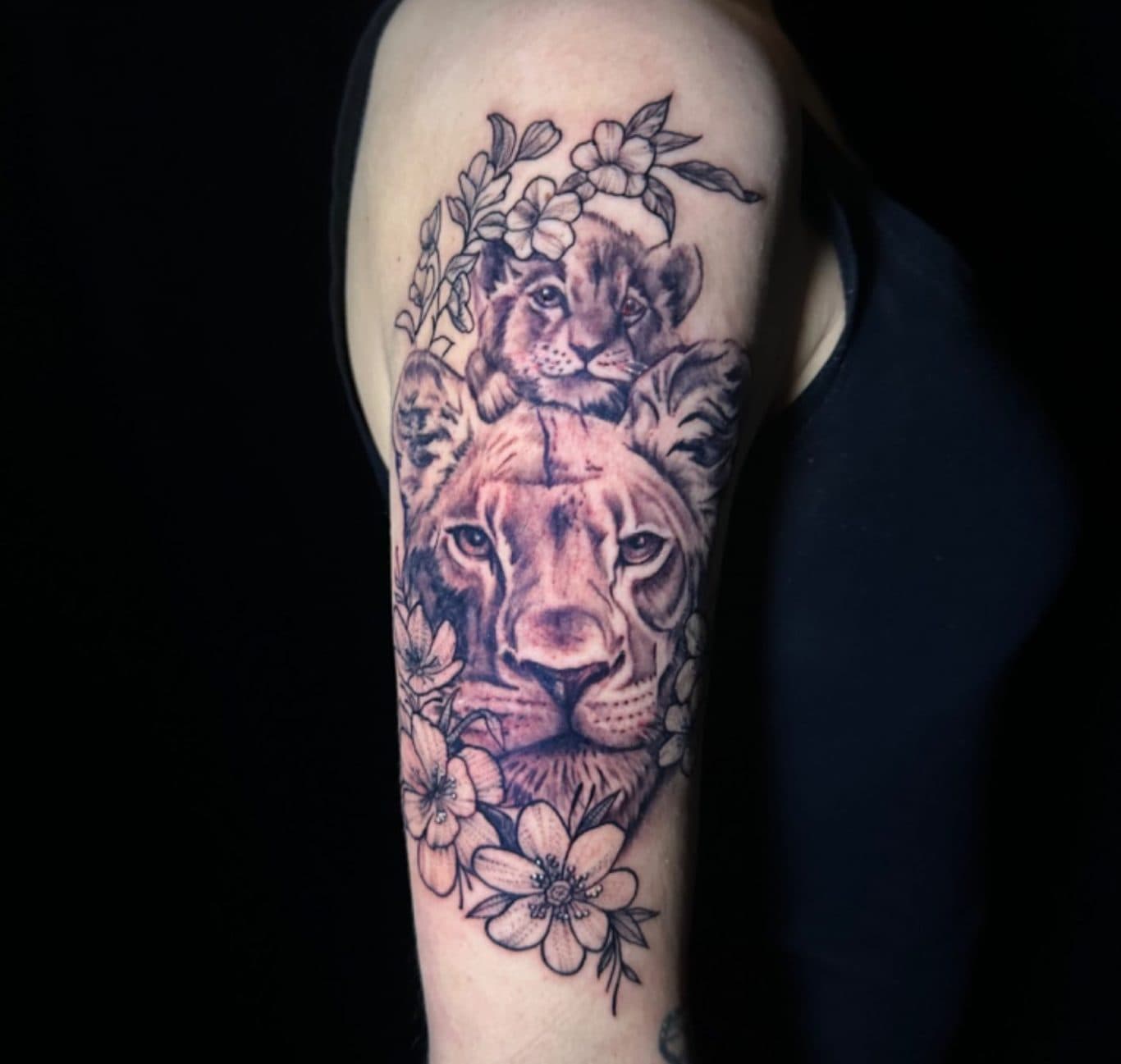 Realistische leeuwin met welp en bloemen op bovenarm.