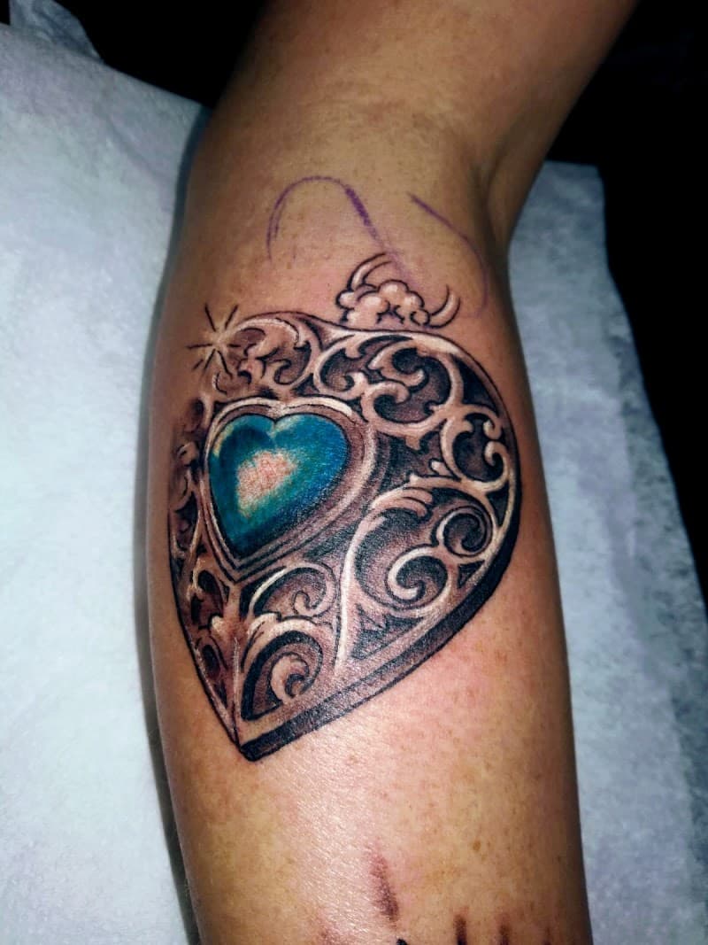 Realistisch hartvormig medaillon met blauwe edelsteen en filigraan.