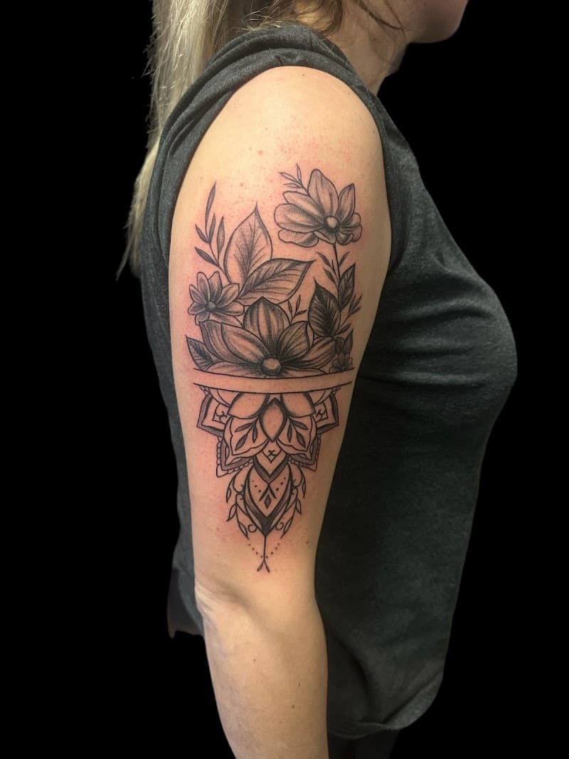 Zwart-wit bloemen en mandala tattoo op bovenarm.