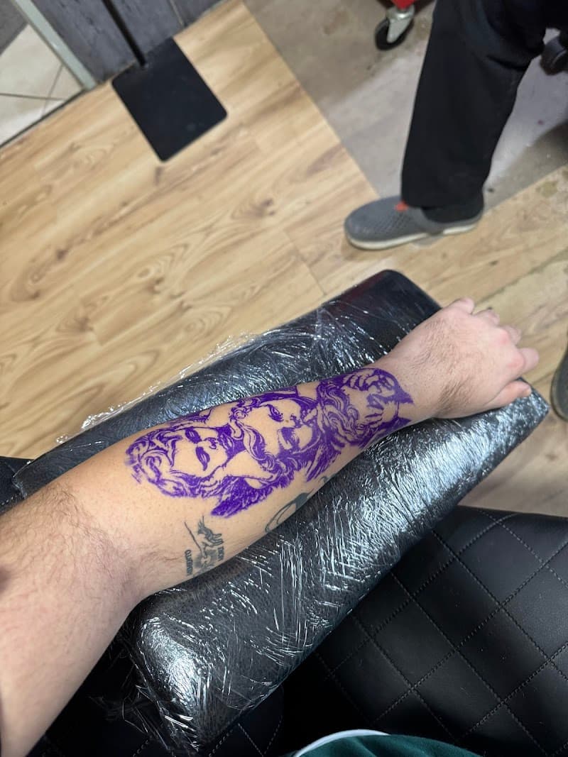 Paarse stencil van religieus tafereel op onderarm.