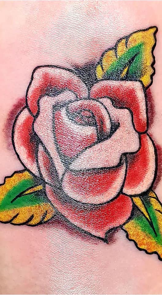 Close-up van een traditionele roos tattoo in rood, groen en geel.