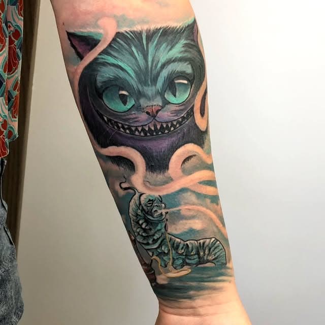 Kleurrijke Alice in Wonderland tattoo met Cheshire Cat en Rups op onderarm.